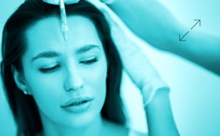 Person erhält eine Injektion in die Stirn, Hände mit Handschuhen halten den Kopf.