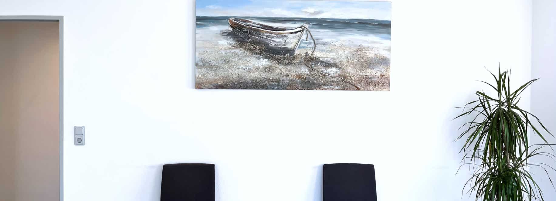zwei stuehle unterm ruderboot mit jukapalme zur rechten
