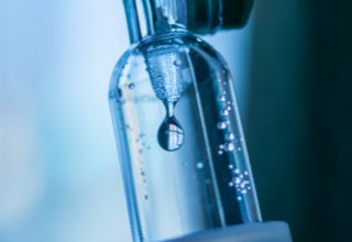 Nahaufnahme eines Infusionsbeutels mit Tropfen, die durch ein transparentes Rohr fließen.