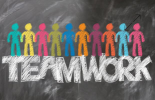 Bunte Figuren stehen auf dem Wort "TEAMWORK" vor einem schwarzen Hintergrund.