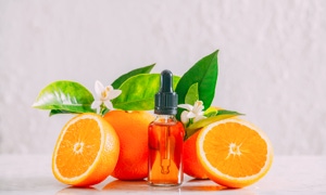 Orangen und grüne Blätter mit einer kleinen Flasche mit Pipette in der Mitte.