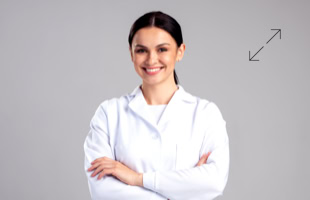 Frau in weißem Kittel mit verschränkten Armen vor grauem Hintergrund.