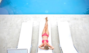 Person in rotem Badeanzug liegt auf einer Sonnenliege neben einem Pool, mit zwei leeren Liegen daneben.