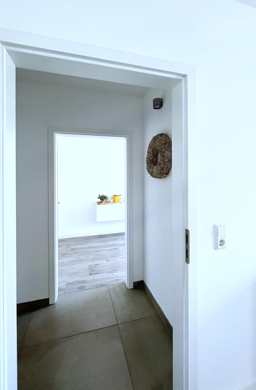 weitlaeufig wirkender blick von einem behandlungsraum ueber den flur zum naechsten praxiszimmer aus stafiert mit unaufdringlicher dekoration