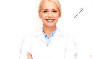 Eine lächelnde Person in einem weißen Laborkittel mit verschränkten Armen.