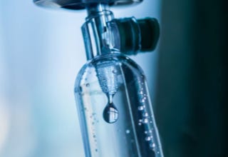 Nahaufnahme eines Tropfens, der aus einem Infusionsbeutel fällt.